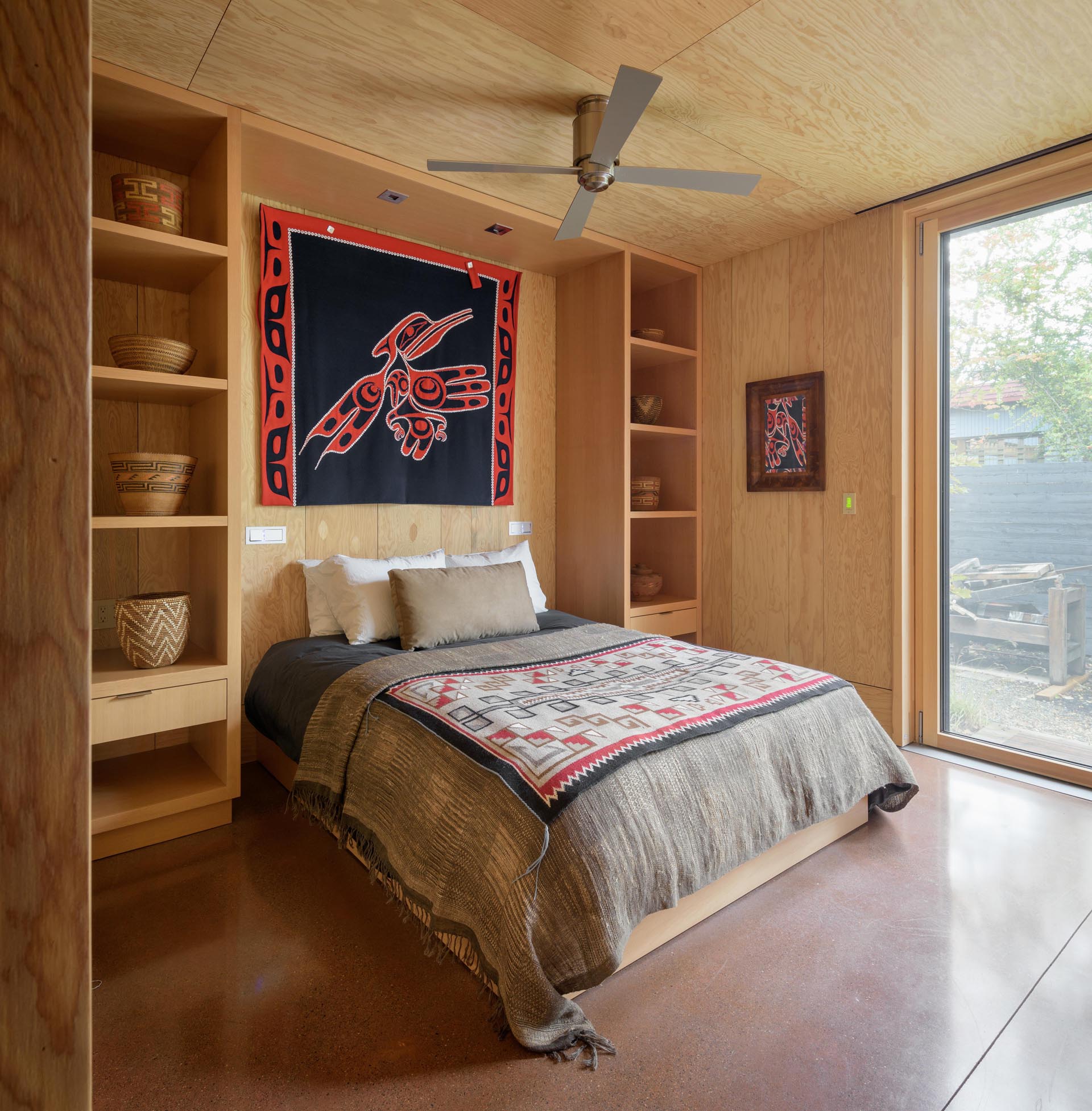 Современная спальня-каюта с бетонным полом и встроенными стеллажами.
