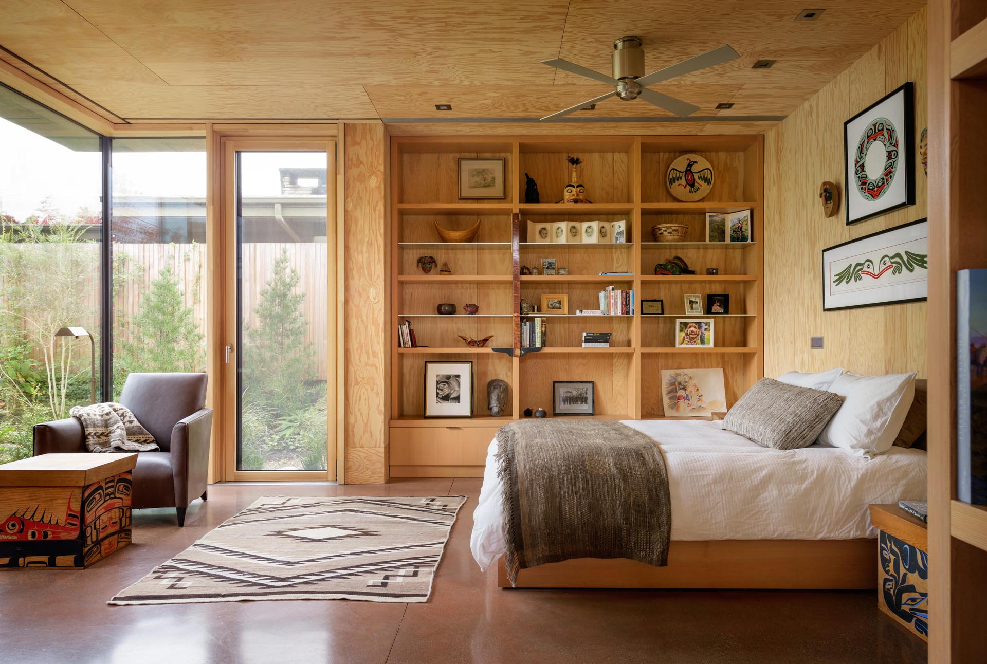 Спальня с бетонным полом и деревянными стеллажами.