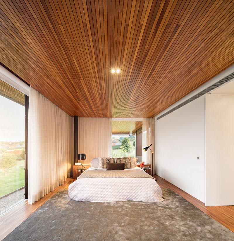 Современная спальня с деревянным потолком.