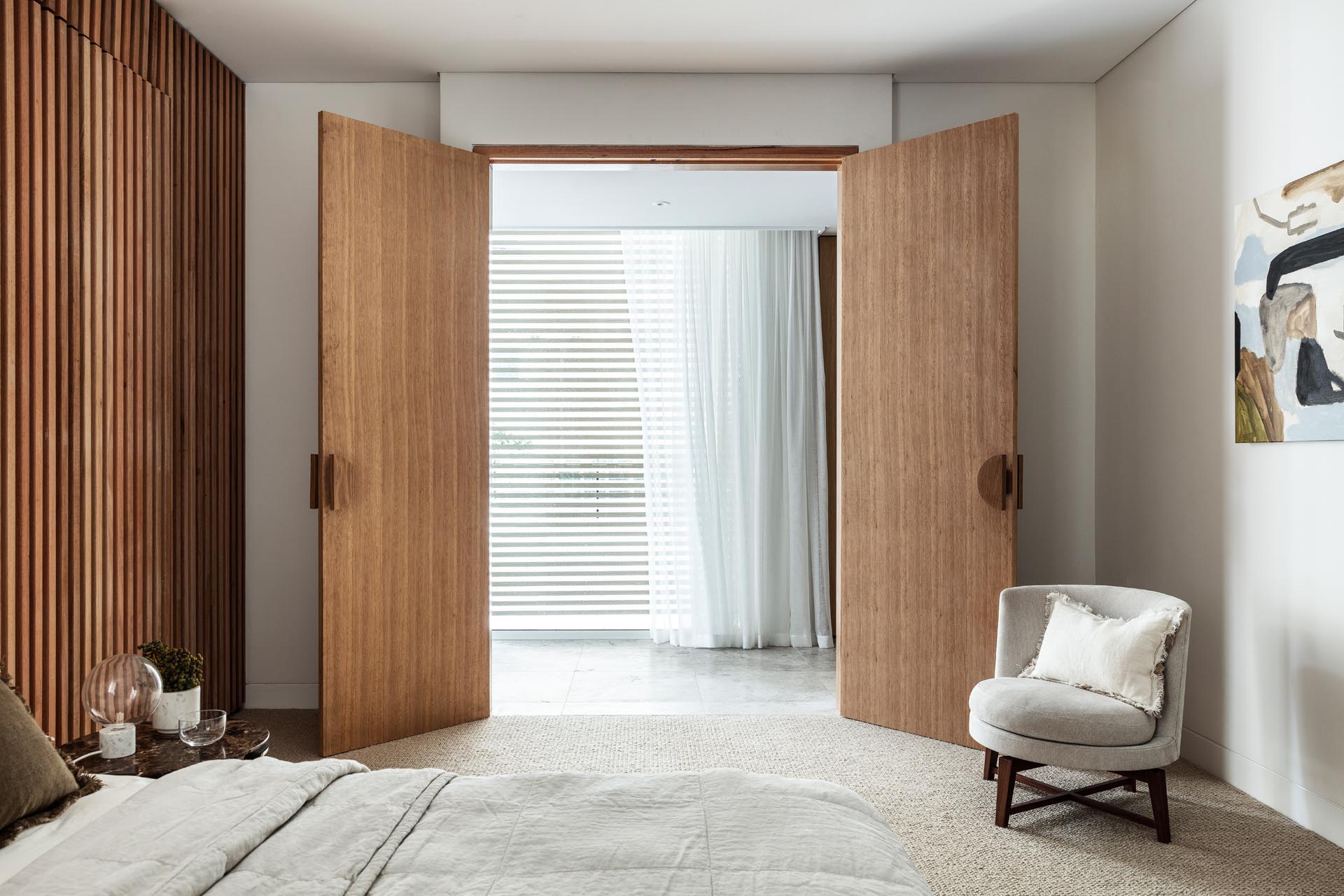 Две деревянные двери открываются в эту современную спальню, где стена из деревянных реек была использована для создания акцентной стены за кроватью.