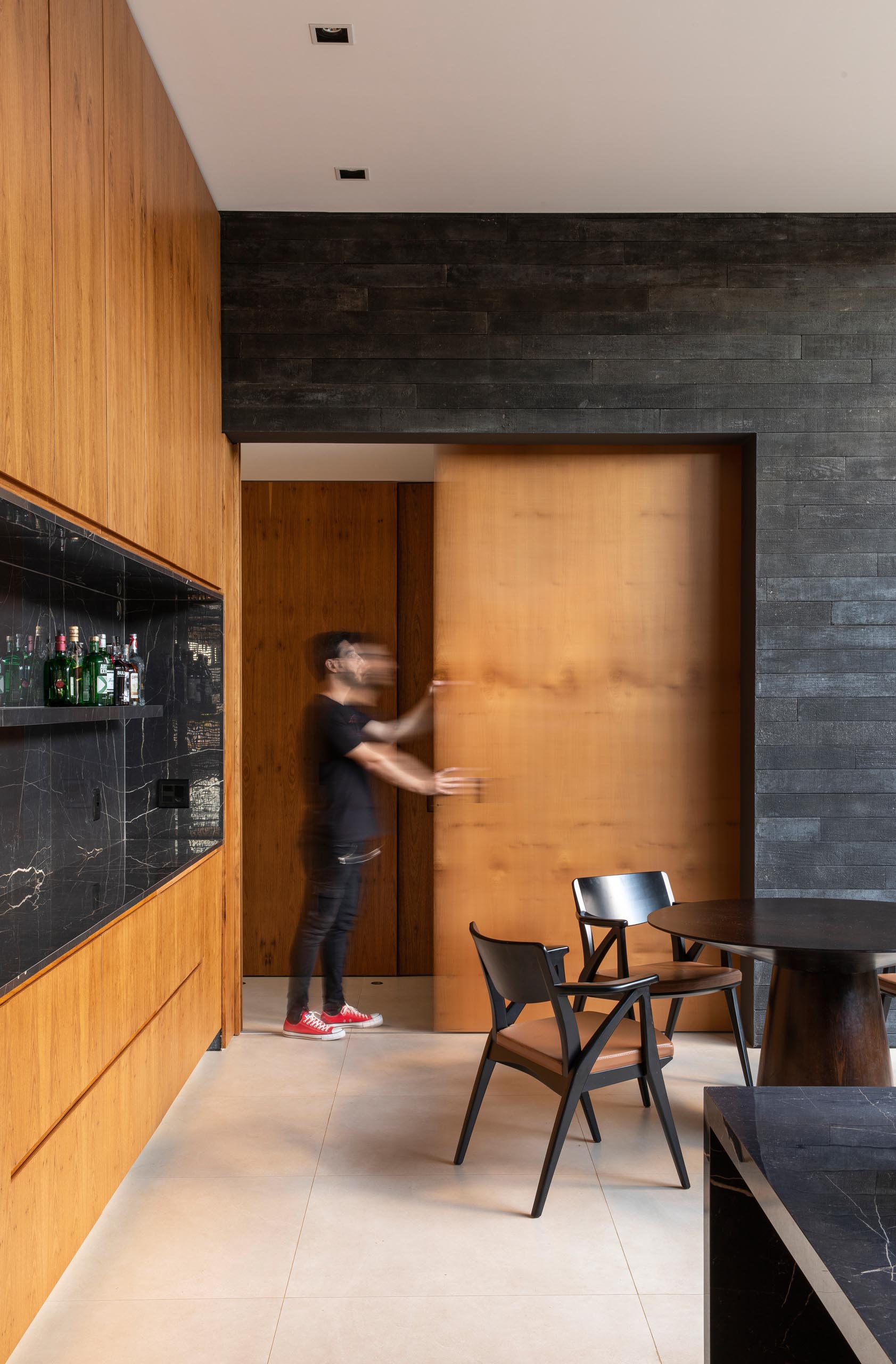 Современная кухня из черного и дерева с раздвижной дверцей.