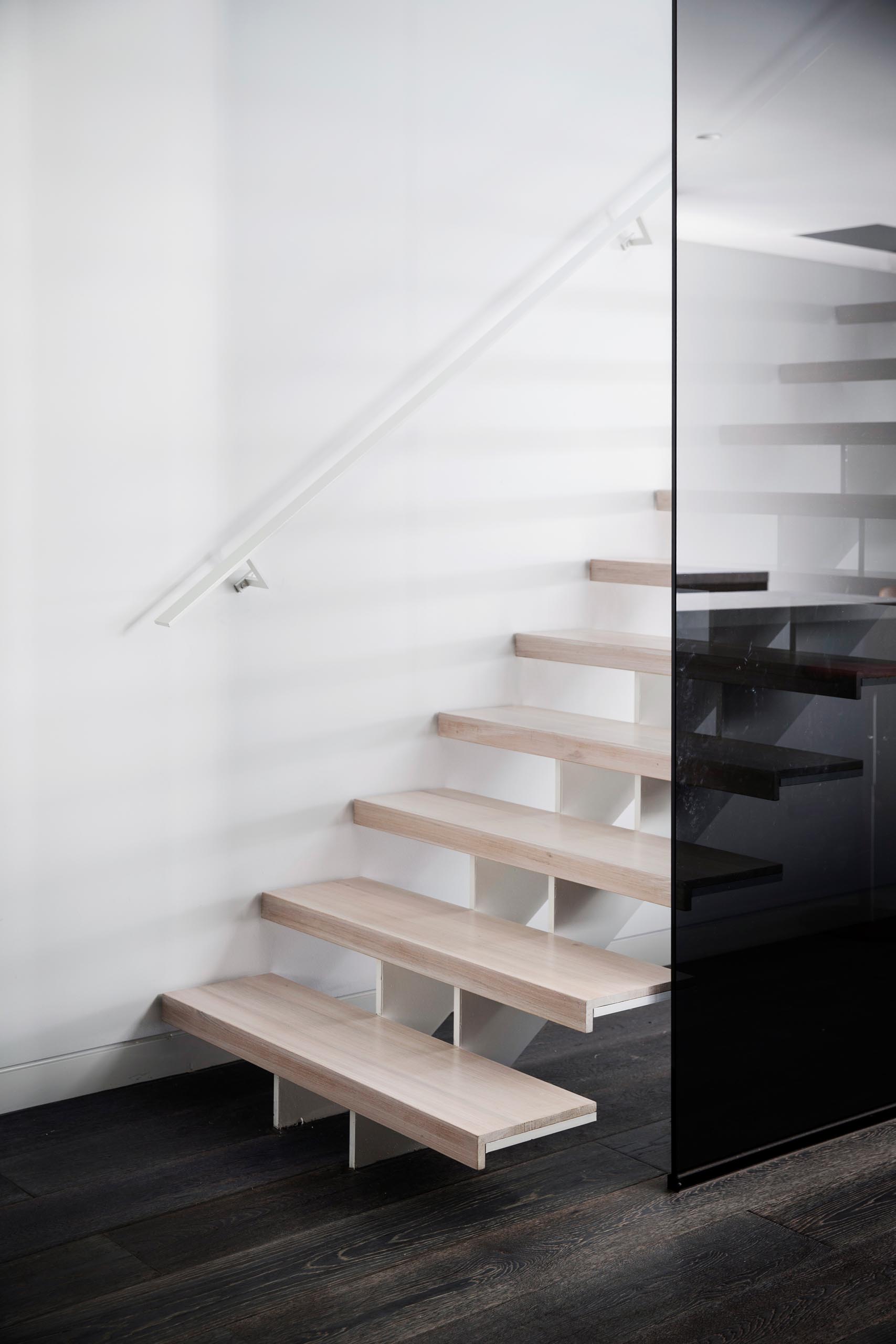 Современные лестницы из светлого дерева с белой стальной опорой и подходящими перилами.