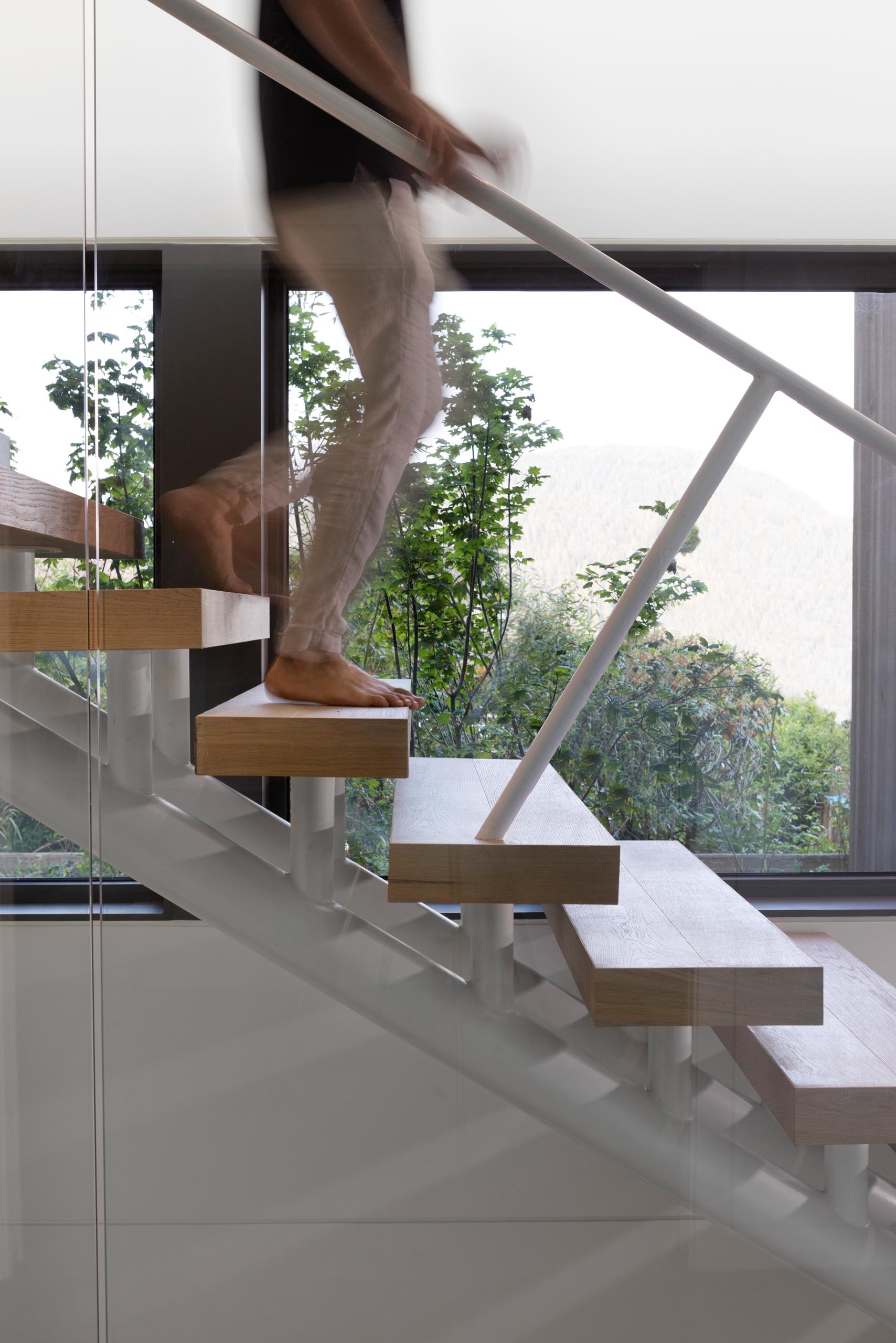 Деревянные ступени лестниц поддерживаются белой рамой, а стекло используется в качестве элемента безопасности, а также позволяет свету из окна проходить внутрь.