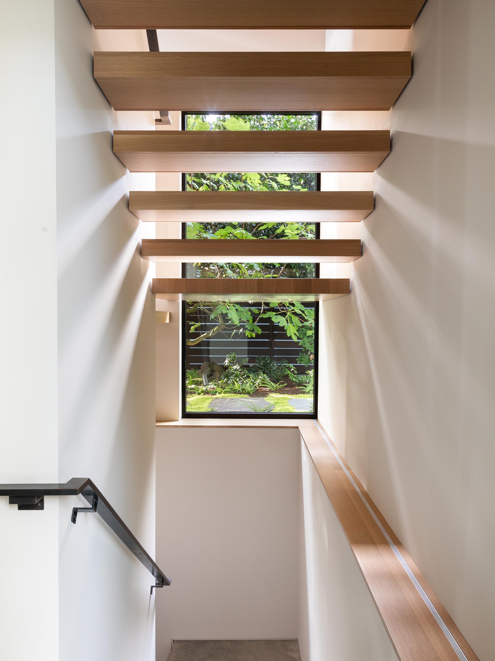 Деревянная лестница соединяет верхние социальные зоны этого современного дома со спальнями и ванными комнатами, расположенными на нижнем уровне.