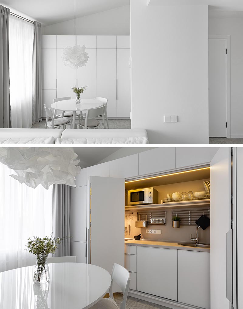 В этих современных минималистичных белых апартаментах кухня скрыта в шкафу в обеденной зоне. #MinimalistKitchen #HiddenKitchen #KitchenDesign