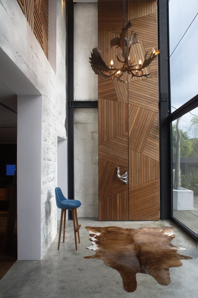 Полосы из светлого дерева, расположенные геометрическим образом, составляют эти двери высотой 23 фута, ведущие в кабинет дома, а скульптурные металлические дверные ручки помогают открыть дверь.