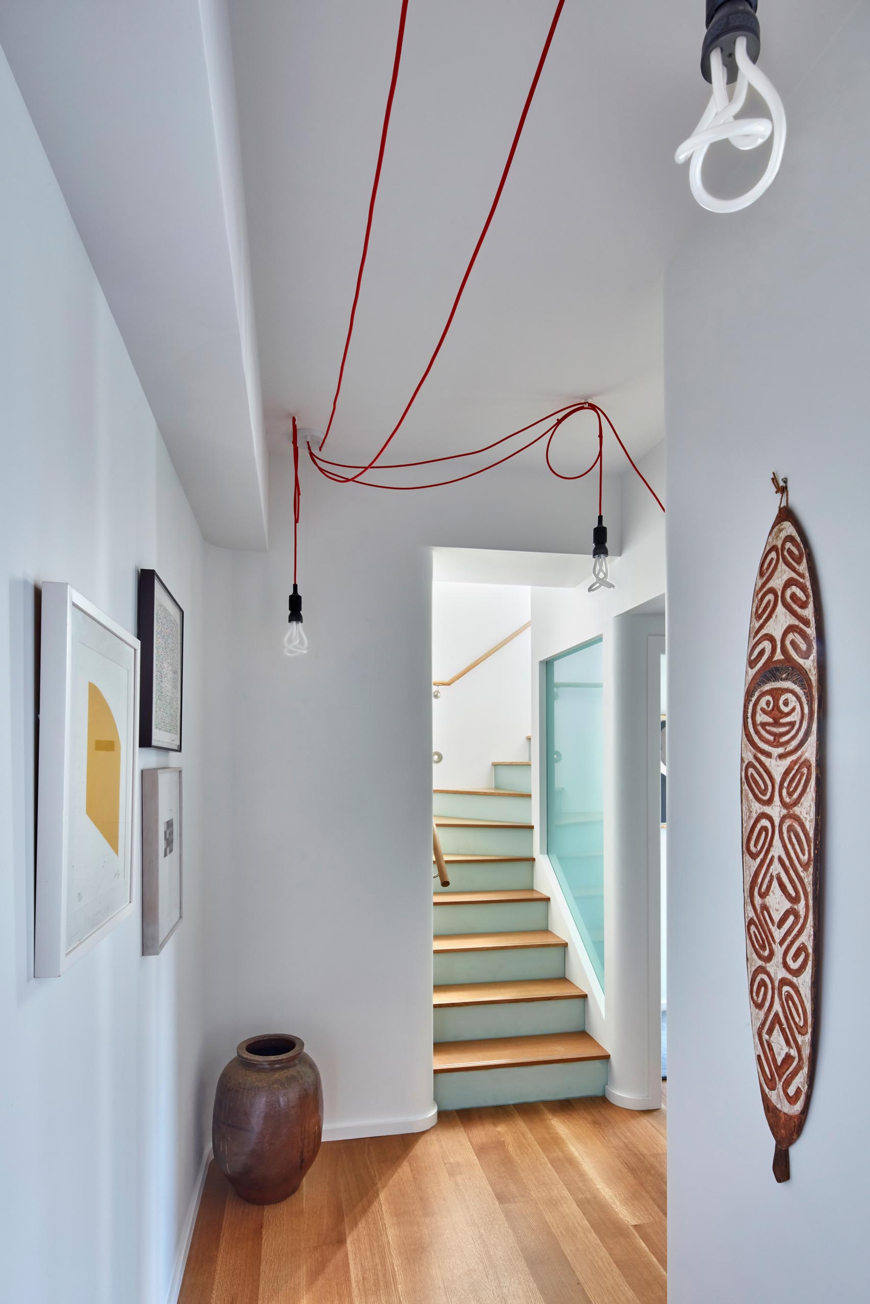 Лестница с деревянными ступенями ведет в коридор с произведениями искусства.