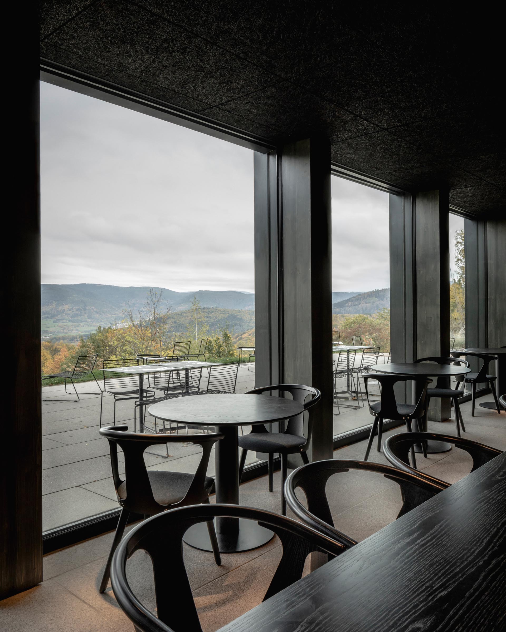 Современный гостиничный ресторан с элементами из темного дерева и большими окнами.