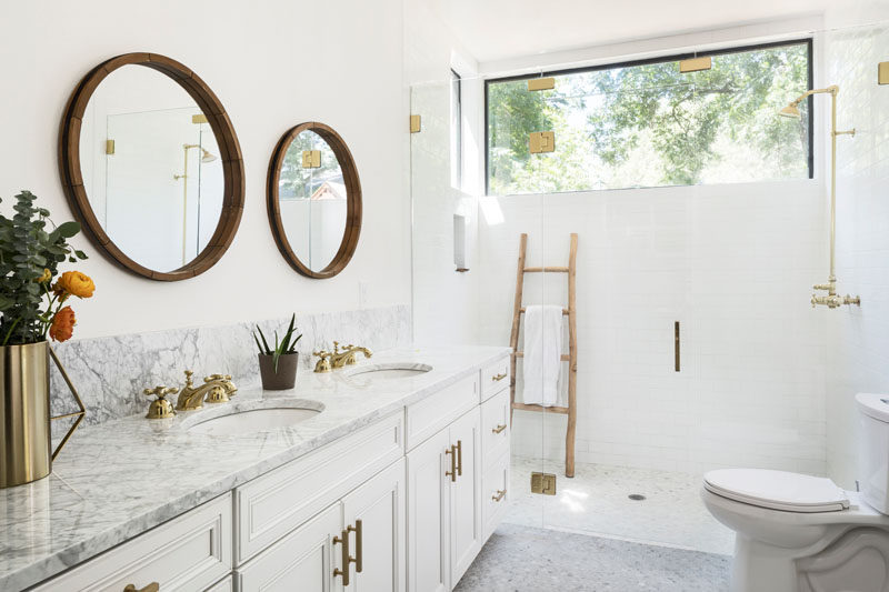 В этой современной ванной комнате круглые зеркала висят над двойной раковиной, отделанной каррарским мрамором, а стеклянная душевая кабина позволяет естественному свету из окна течь через пространство. # ВаннаяДизайн # БелаяВанная