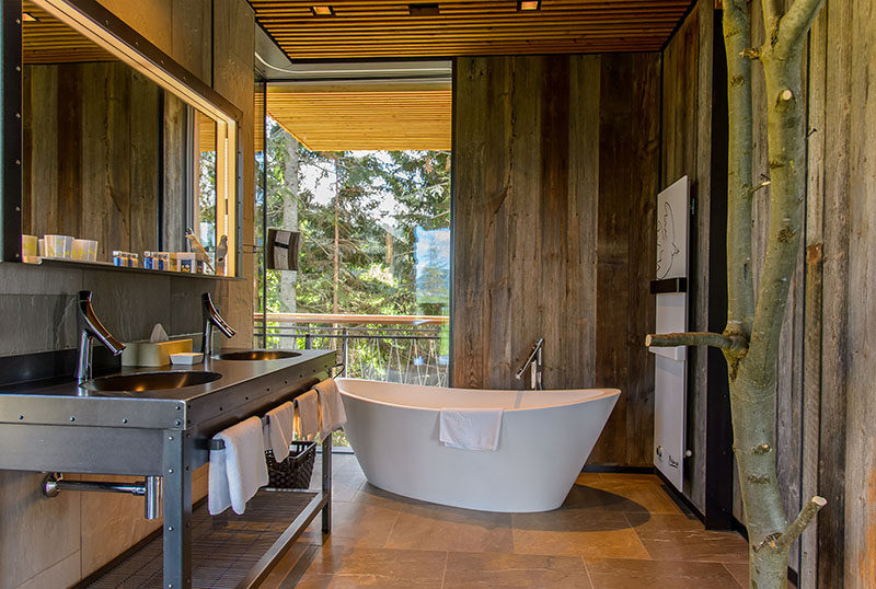 В этой современной ванной комнате, оформленной в загородном стиле, отдельно стоящая ванная расположена так, что через угловые окна от пола до потолка открывается вид на деревья. #RusticModern # Ванная # Окна # Ванна