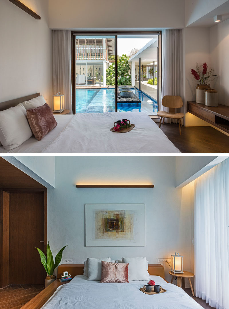  В современной спальне у бассейна простая деревянная лампа украшает стену, раздвижная стеклянная дверь позволяет естественному свету и ветру проникать в комнату 