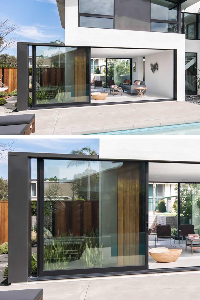 Стеклянная дверь во всю высоту с черной рамой открывает гостиную этого современного дома и соединяет ее с патио, окружающим бассейн. #GlassWall #Architecture #SlidingWall #ModernHouse