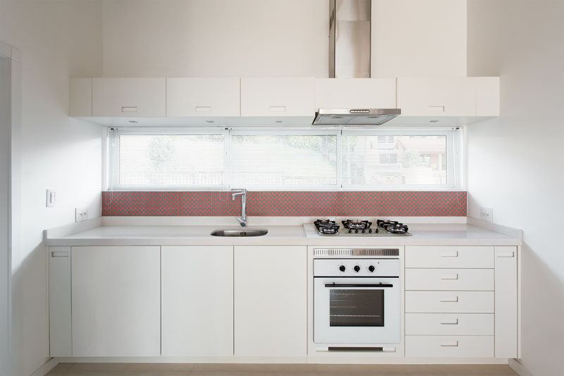  В этой маленькой кухне простые белые шкафы почти гармонируют с белыми стенами, а фартук тонок красного. 