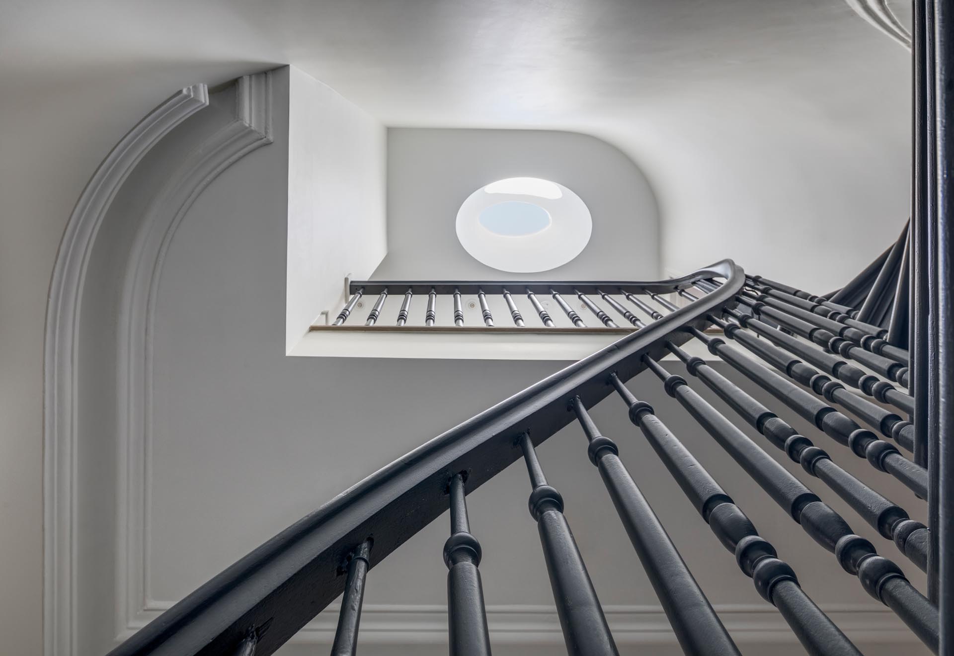 Лестница с серым поручнем и мансардным окном.