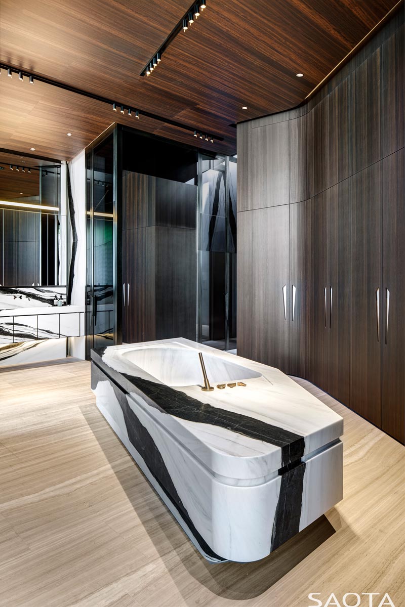 В этой современной ванной комнате высокие деревянные шкафы расположены вдоль стен, а каменная ванна расположена в центре. # Современная ванная # Дизайн ванной # Каменная ванна