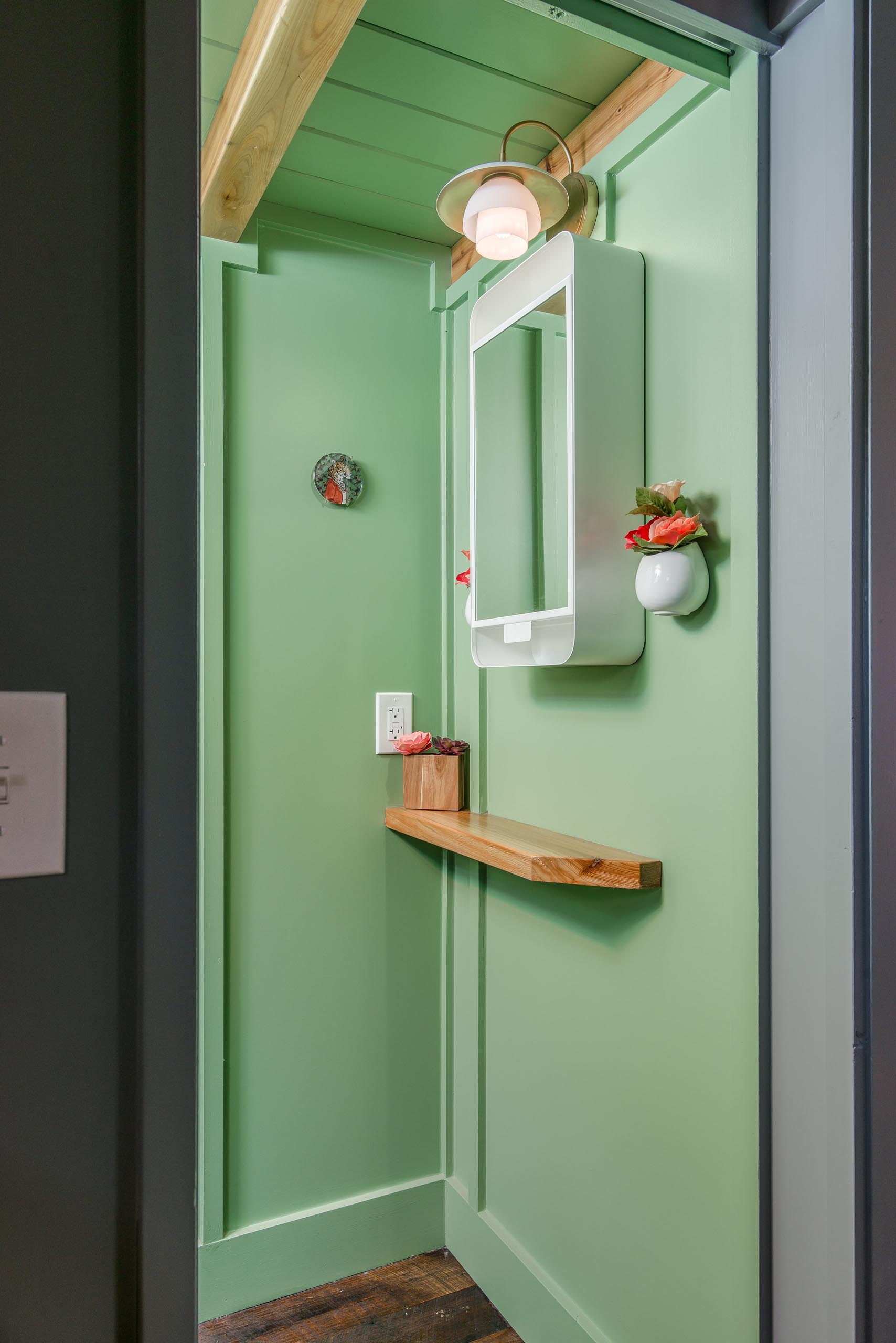 Эта крошечная ванная комната в доме скрывается за раздвижной дверью-карманом и включает в себя пастельно-зеленую отделку, безводный туалет, туалетный столик и душ.