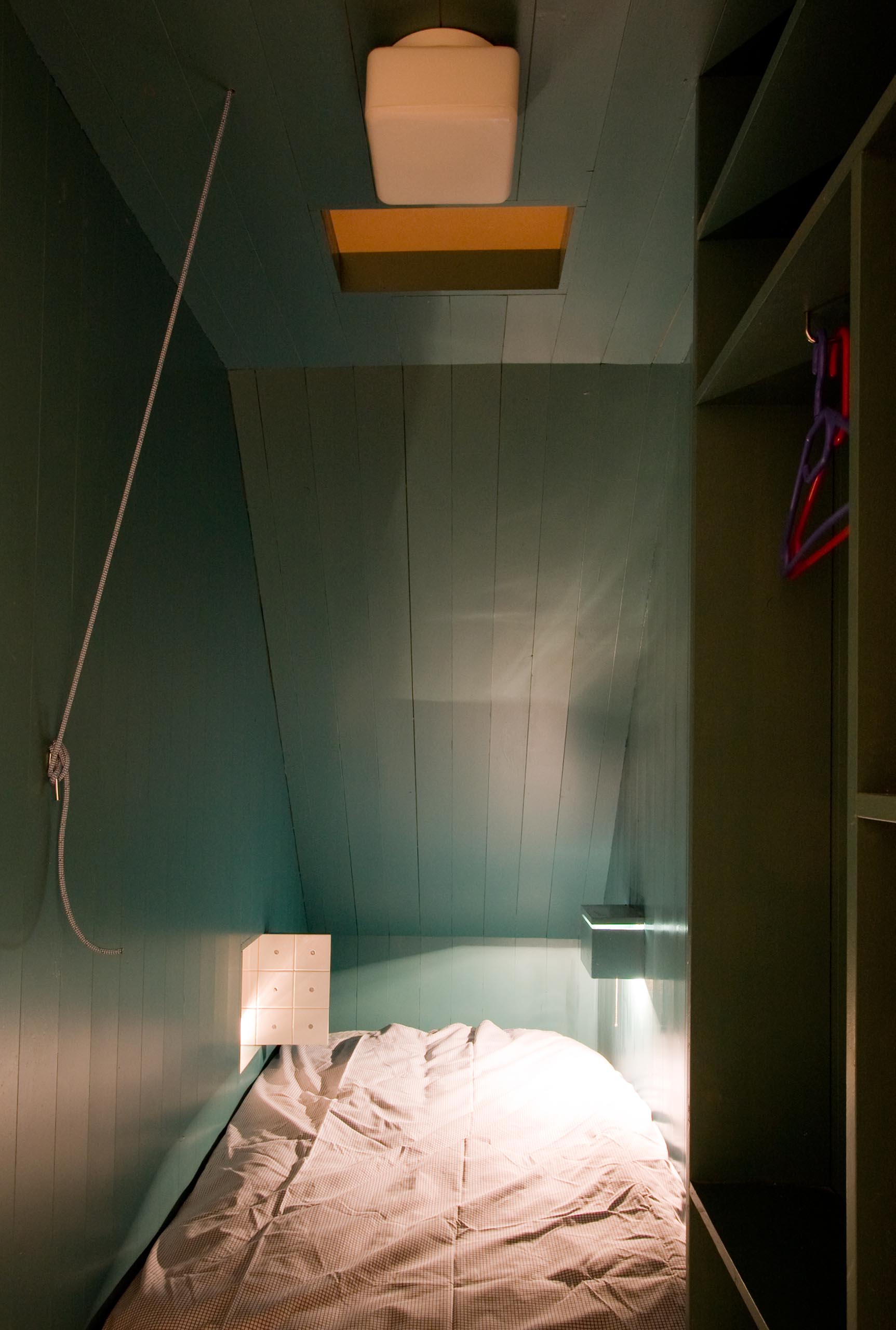 Современная бирюзово-голубая спальня с небольшим окном, выходящим в гостиную.