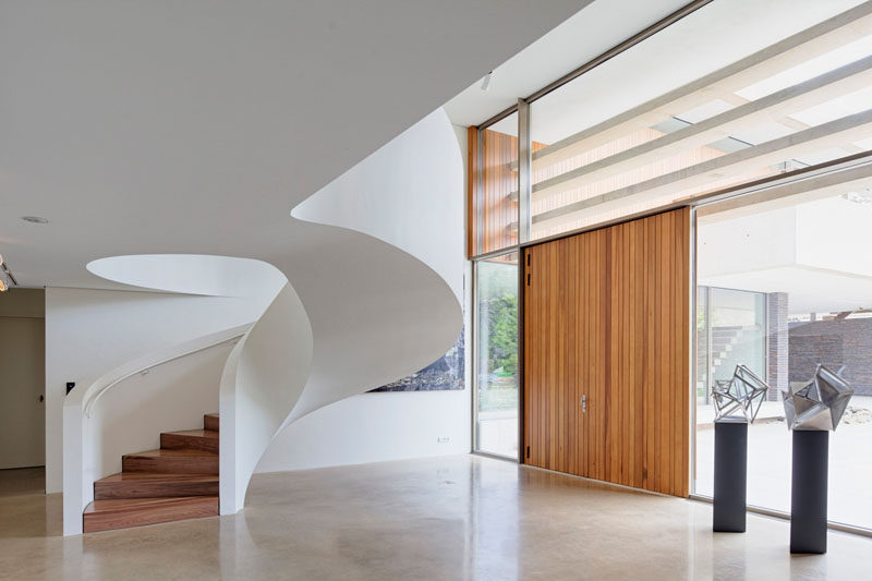 Эта современная винтовая лестница белого цвета с белыми перилами и деревянными ступеньками делает дизайн простым и чистым.