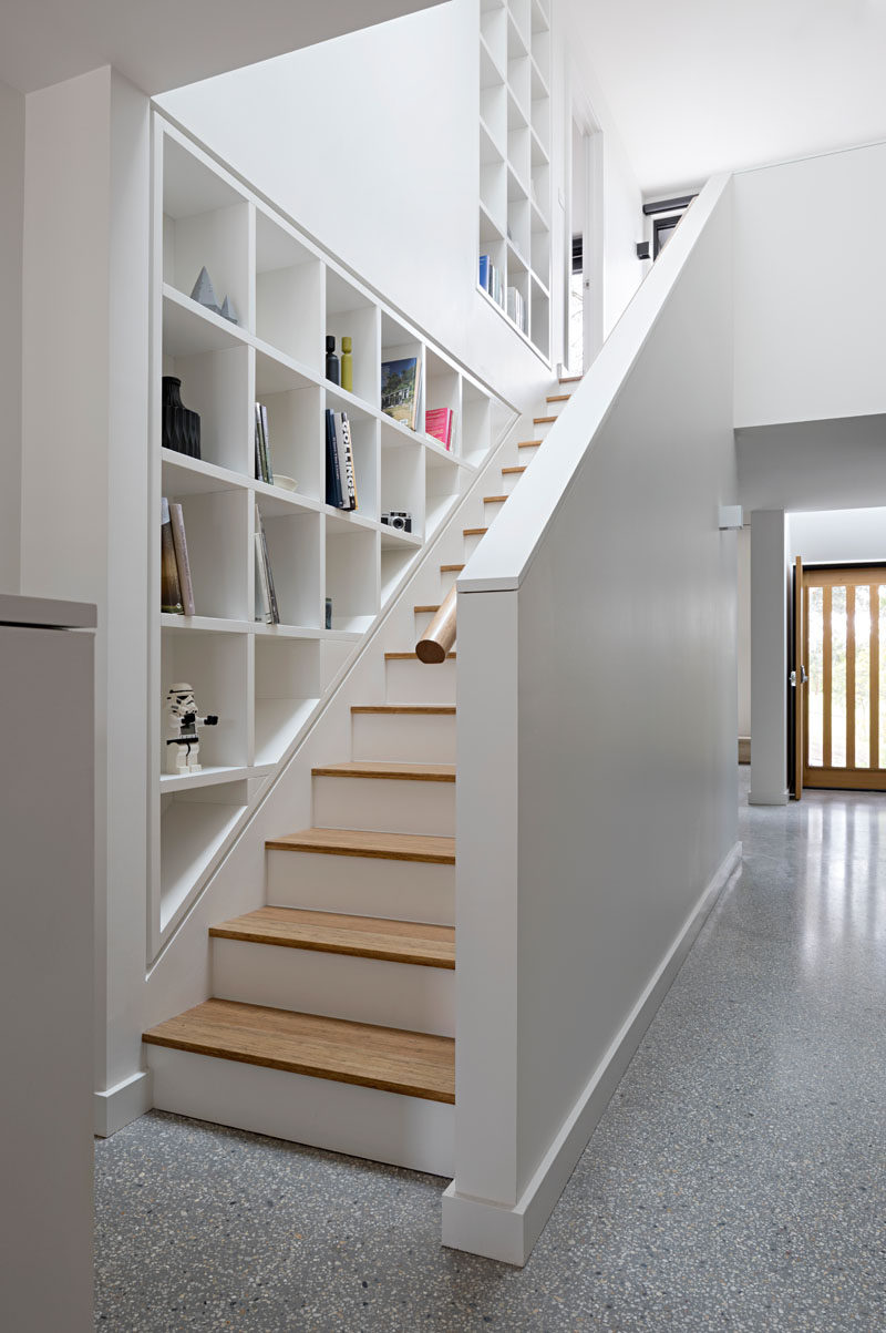 Эти белые и деревянные лестницы выложены специально разработанными стеллажами для демонстрации личных вещей, а верхний люк наверху дает много естественного света.