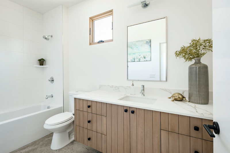 В этой современной ванной комнате есть небольшое окно с деревянной рамой, которое соединяется с деревянной мебелью туалетного столика. # Современная # Белое и ДереваВанная # Дизайн ванной