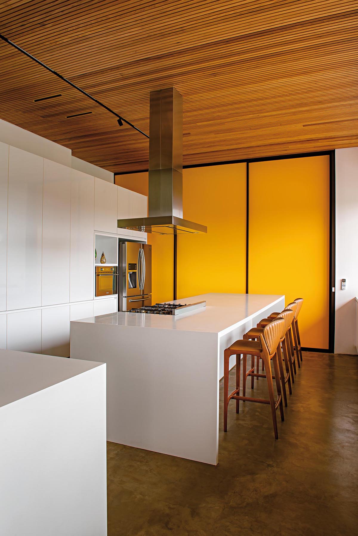 На этой современной кухне есть минималистские белые шкафы и островки без оборудования. Ярко-желтая стена с акцентом создает смелое и красочное впечатление.