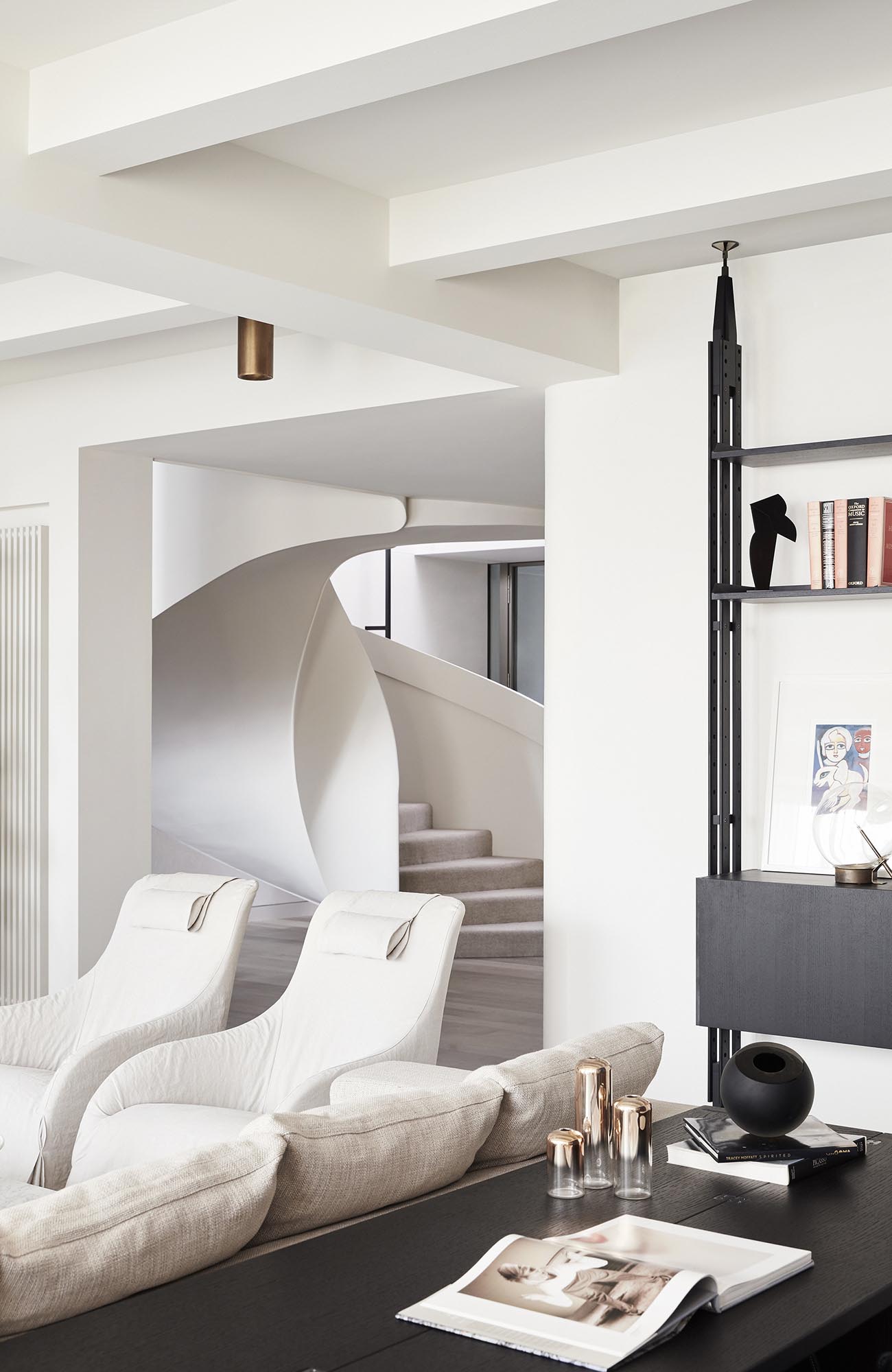 Современный интерьер с яркой мебелью и белой винтовой лестницей.