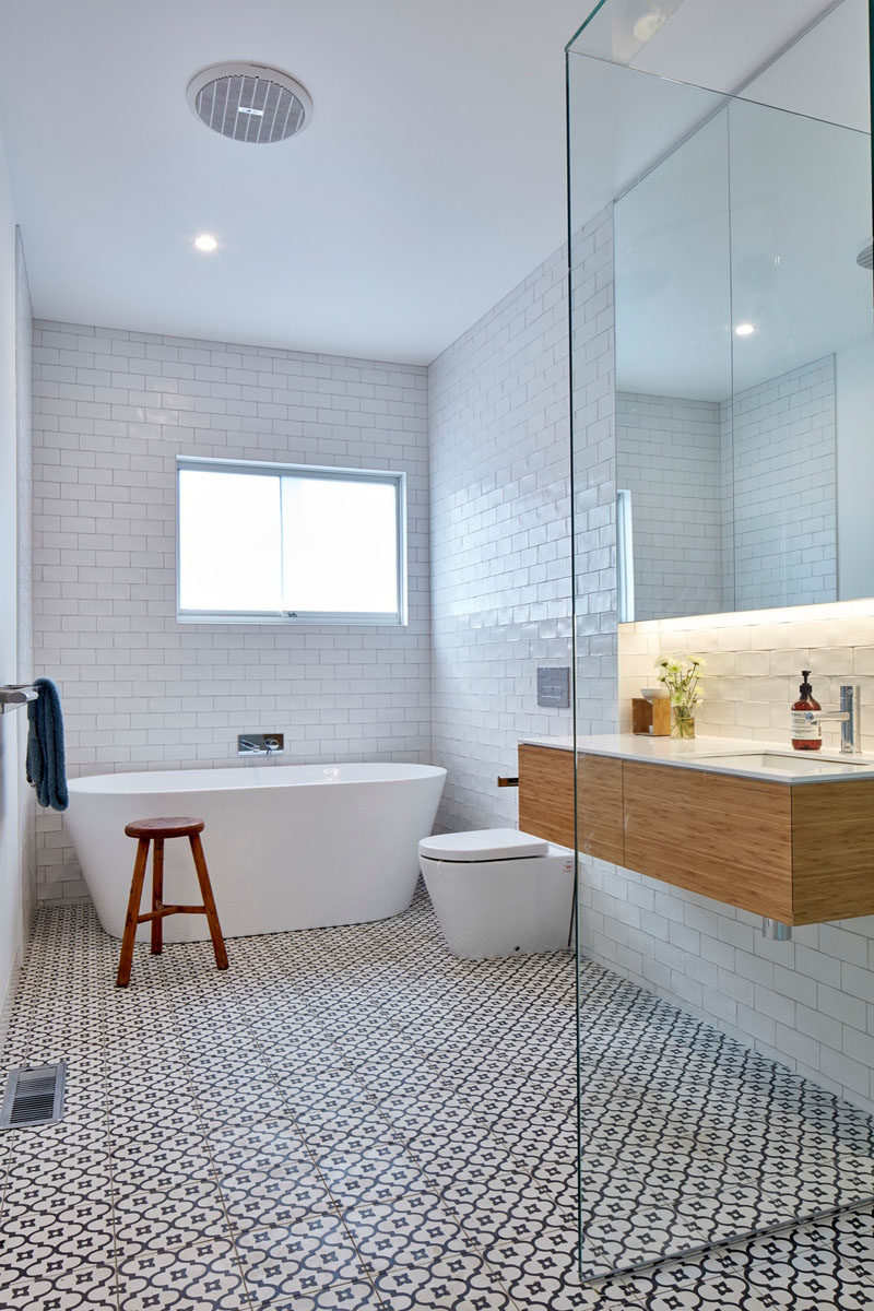 Стены этой ванной комнаты выложены белой плиткой метро, ​​а на полу использована декоративная плитка.