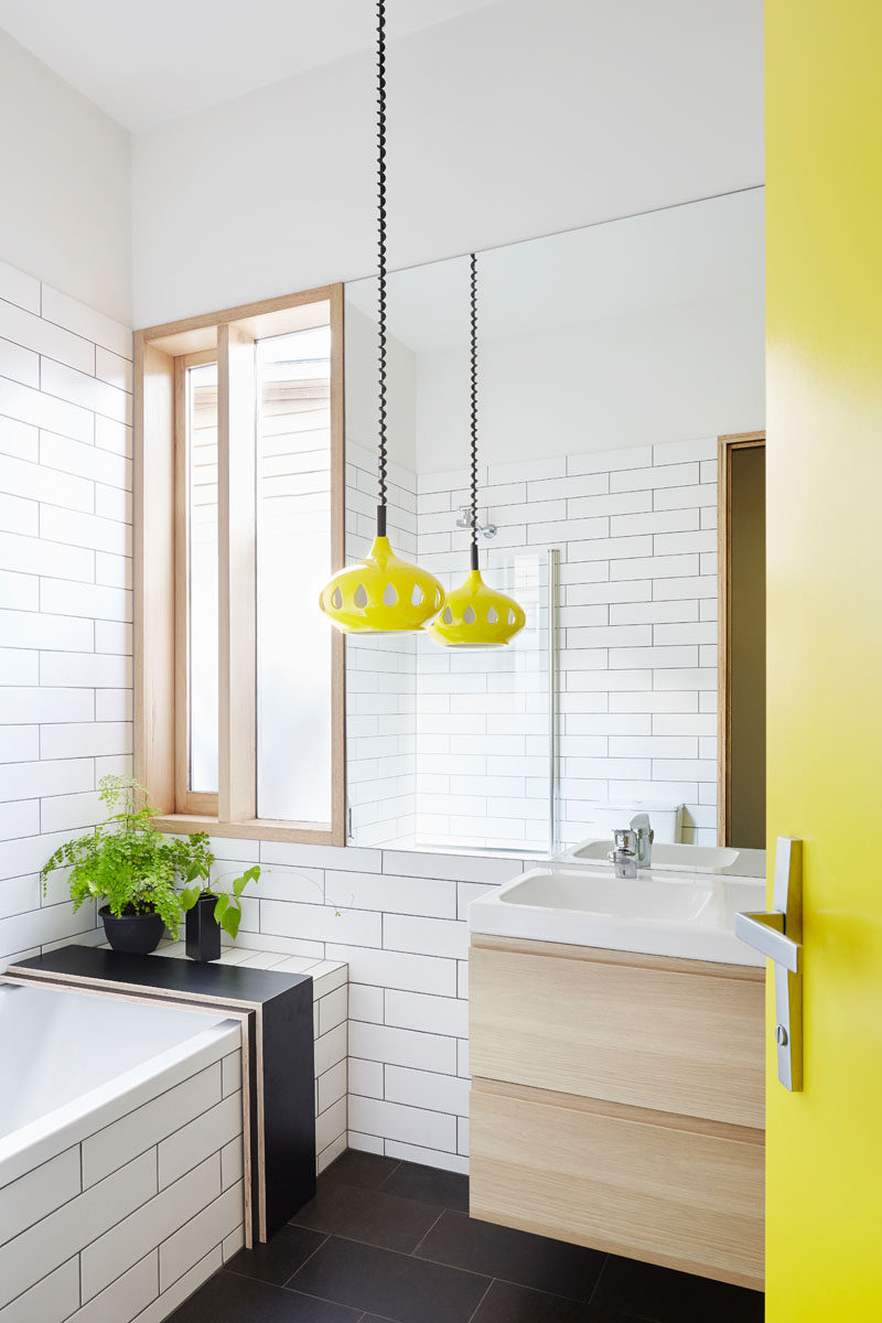  Эта современная ванная комната имеет ярко-желтую дверь, которая сочетается с забавным подвесным светильником того же цвета, а остальная часть ванной комнаты черно-белая. 