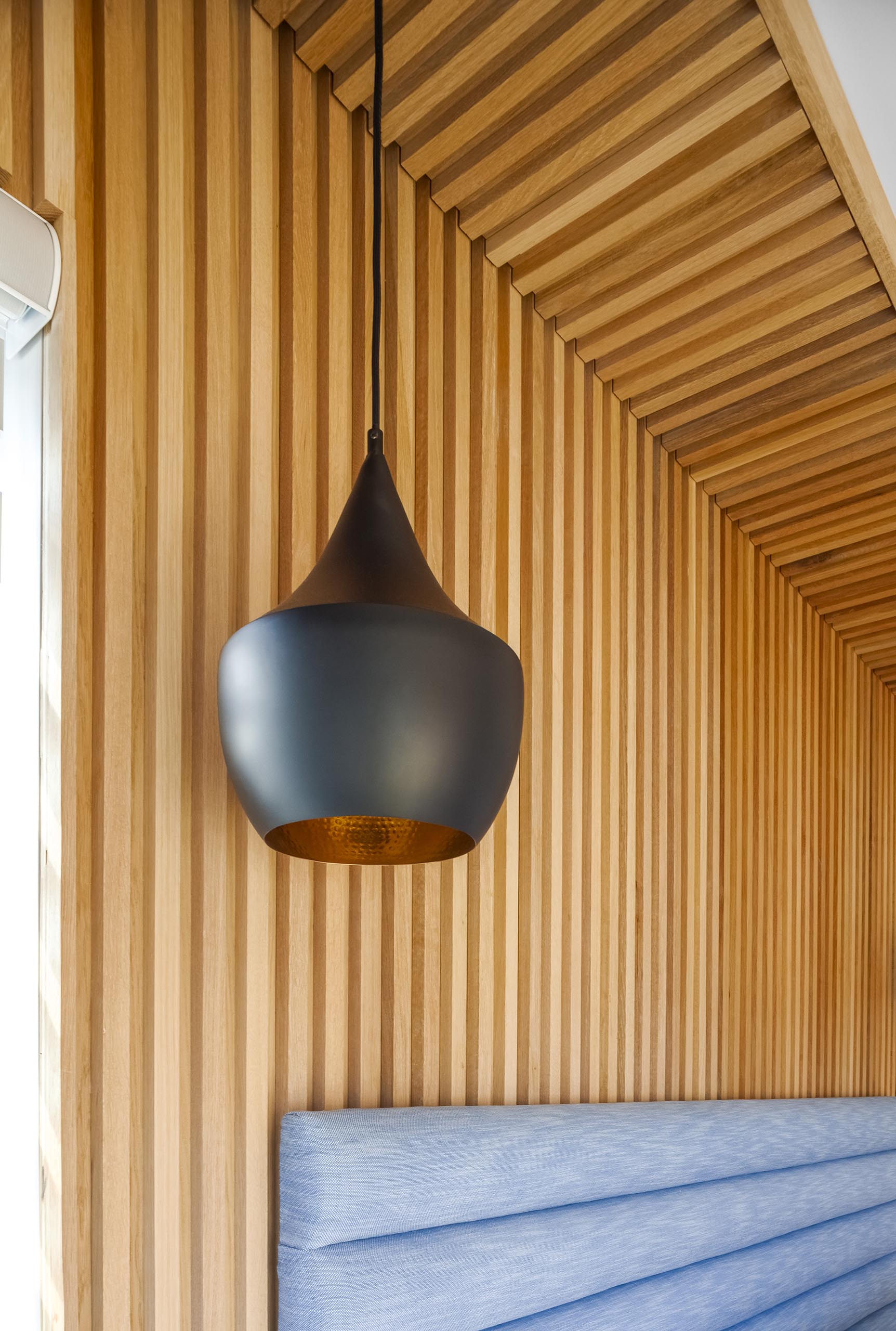 Стена с деревянным акцентом и современный черный подвесной светильник.
